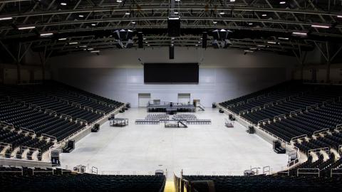 A wide-shot of the CCC arena, featuring a digital display board, a large array of seating, open arena space, and high-tech audio equipment.