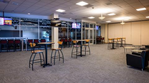 Hospitality suite with high top tables and view of arena.