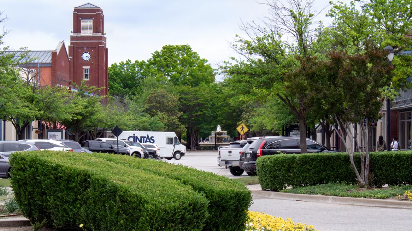 Shops line the sides of a street in the Firewheel Mall, the clock tower and fountain on the horizon.