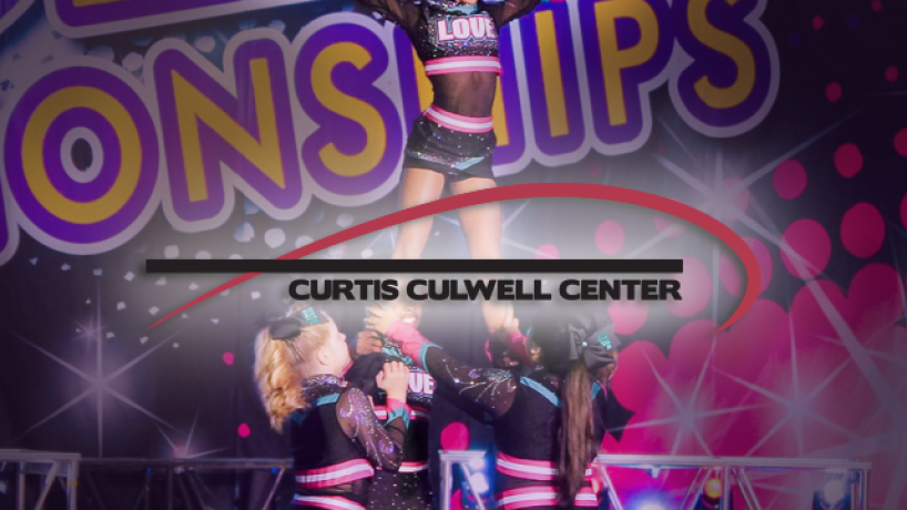 A group of young cheer leaders holds a different cheerleader in the air while she poses dramatically for a contest.