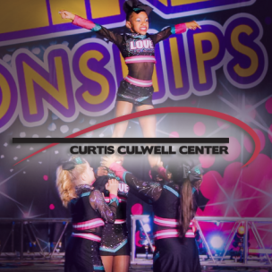 A group of young cheer leaders holds a different cheerleader in the air while she poses dramatically for a contest.